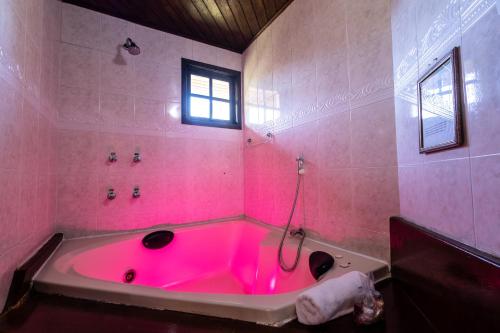 uma banheira rosa na casa de banho com uma janela em Pousada 3 Pinheiros em Campos do Jordão