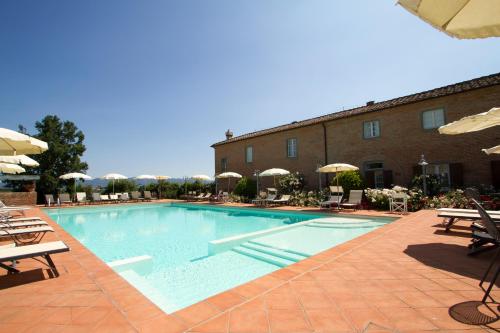 a swimming pool with chairs and umbrellas next to a building at Agriturismo S.Angelo in Foiano della Chiana