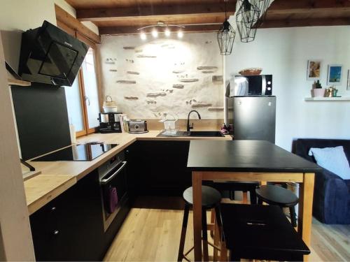 une cuisine avec un évier, une table et un réfrigérateur dans l'établissement Maison cosy en hyper-centre, à Agen