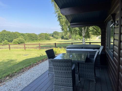 a patio with a table and chairs on a porch at Chestnut, 6 Fingle Glen Lodges in Holcombe Burnell