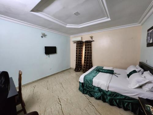 a hotel room with a bed and a tv at Nue-Crest Hotels & Suites in Enugu