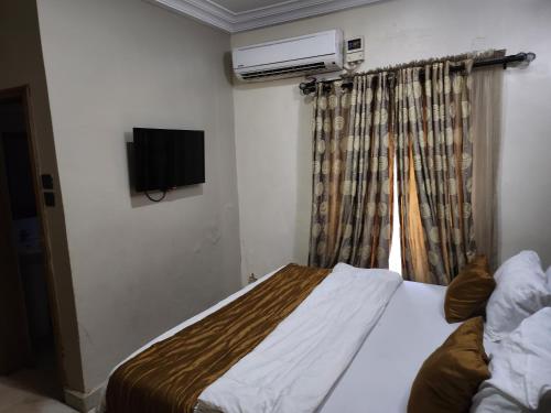 a small bedroom with a bed and a television at Nue-Crest Hotels & Suites in Enugu