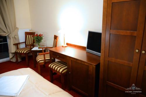 a room with a desk with a television and a bed at Dworek Jamneński in Łazy