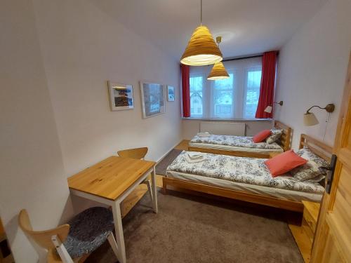 mały pokój z 2 łóżkami i stołem w obiekcie Apartament Roland w Świeradowie Zdroju