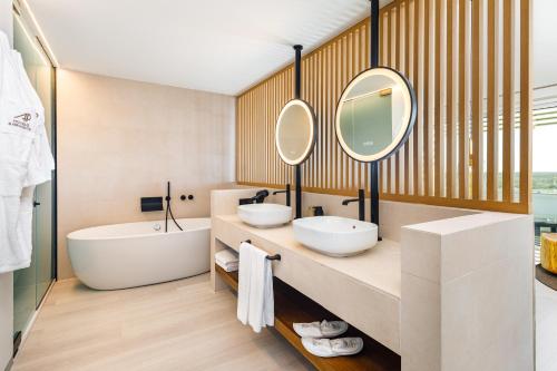 a bathroom with two sinks and a tub and mirror at AP Eva Senses in Faro