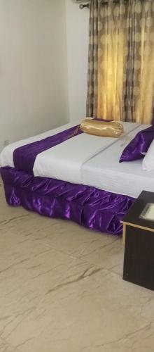 two beds in a room with purple sheets at Nue-Crest Hotels & Suites in Enugu