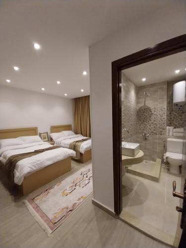 een hotelkamer met 2 bedden en een badkamer bij Eagles Pyramids View in Caïro