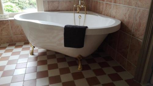 a bath tub in a bathroom with a checkered floor at B&B De Warren in Suawoude