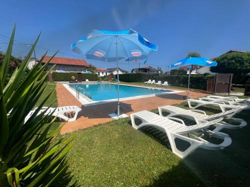 a group of white chairs and umbrellas next to a pool at Complejo la Regalina in Cadavedo