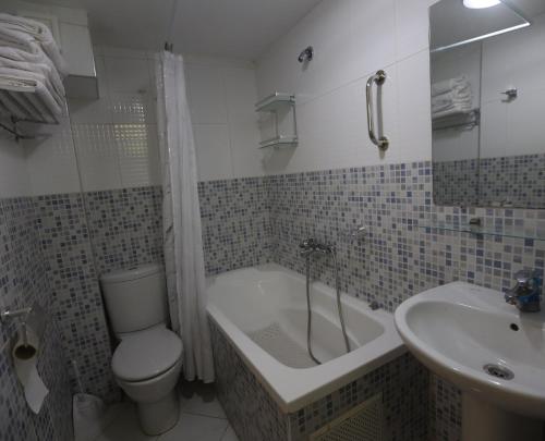 a bathroom with a toilet and a tub and a sink at TAZEKKA PARC HOTEL in Taza