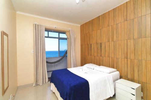 a bedroom with a bed and a window with the ocean at Rio Spot Homes vista praia D047 in Rio de Janeiro