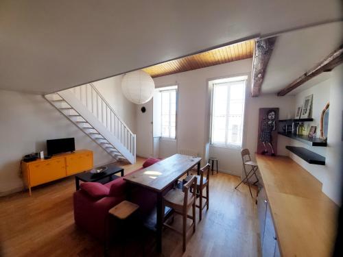 a living room with a table and chairs and a staircase at L'Atelier in La Rochelle