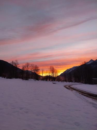 a snow covered field with a sunset in the background at APARTMA 27 in Kranjska Gora