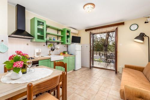 a kitchen and dining room with green cabinets and a table at House Dinka with Pool in Porat