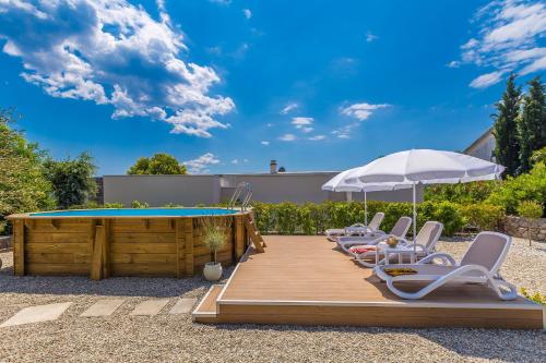 a deck with chairs and an umbrella and a pool at Kuća za odmor Villa Seahorse in Pinezici