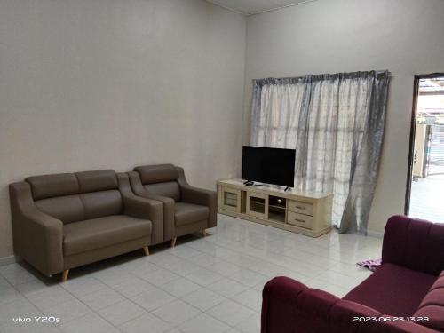 a living room with two chairs and a flat screen tv at Homestay Abdul Kalam in Kalumpang