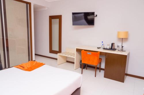 a bedroom with a bed and a desk and a chair at Hotel Embaixador in Beira