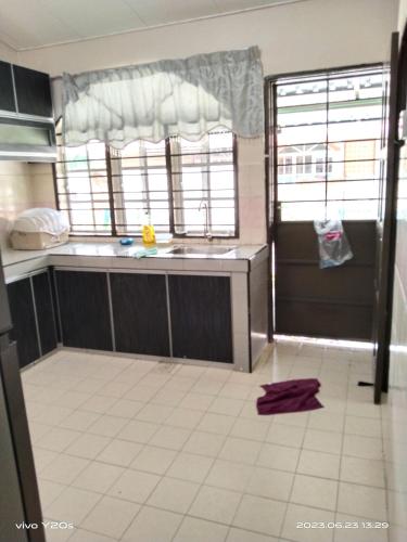 a kitchen with a sink and two windows in it at Homestay Abdul Kalam in Kalumpang
