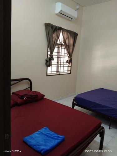 a room with two beds and a table and a window at Homestay Abdul Kalam in Kalumpang