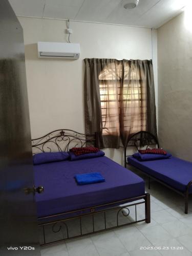 a bedroom with two beds with blue sheets and a window at Homestay Abdul Kalam in Kalumpang