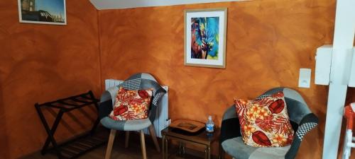 2 Stühle in einem Zimmer mit orangefarbener Wand in der Unterkunft Bienvenue au Faré Hibiscus in Corrombles