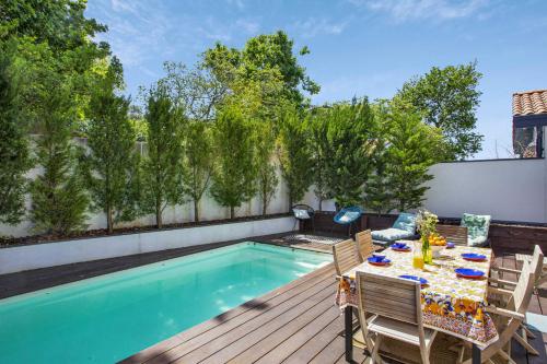 un patio avec une table et des chaises à côté d'une piscine dans l'établissement Villa Miarritze - Welkeys, à Biarritz