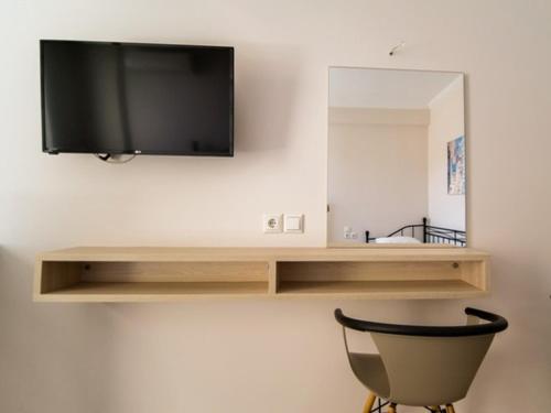 a flat screen tv on a wall with a chair at Vironas Hotel in Himare