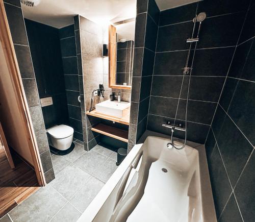 une salle de bain avec une baignoire, un lavabo et des toilettes dans l'établissement L'Aqui Sana, Appartement de standing, au Monêtier-les-Bains
