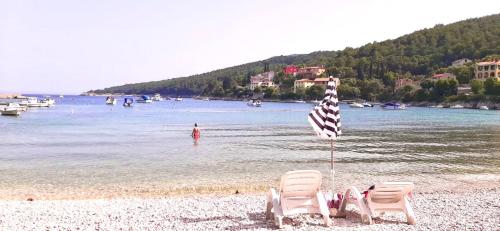 a beach with two chairs and a flag in the water at Villa Una Apartments in Labin