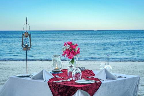 a table on the beach with a vase of flowers at Boutique Hotel Matlai in Michamvi