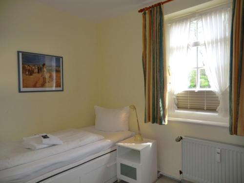 een kleine slaapkamer met een bed en een raam bij Parkstrasse -Whg1 in Wyk auf Föhr