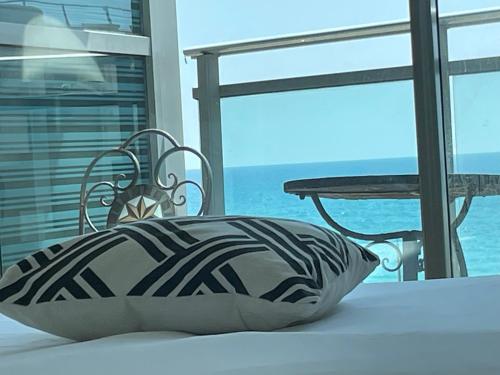 uma almofada sentada numa cadeira ao lado de uma mesa em אוקיינוס במרינה מלון דירות בעלים פרטיים עם נוף לים מרפסת אחד עד שני חדרי שינה וסלון em Herzliya B