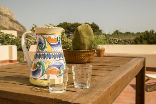 un vaso e due bicchieri su un tavolo di legno di Le Casette del Bosco a Favignana