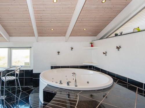 a large white tub in a room with black tiles at 9 person holiday home in Ringk bing in Søndervig