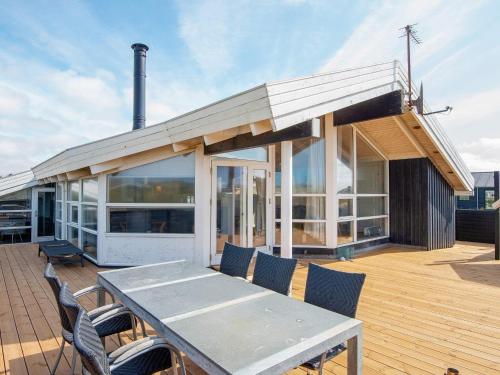 a house with a table and chairs on a deck at 9 person holiday home in Ringk bing in Søndervig