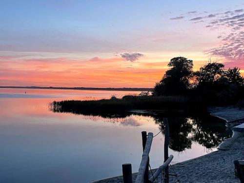 a sunset over a body of water with a fence at sunset cabin on the beach in Wapnica