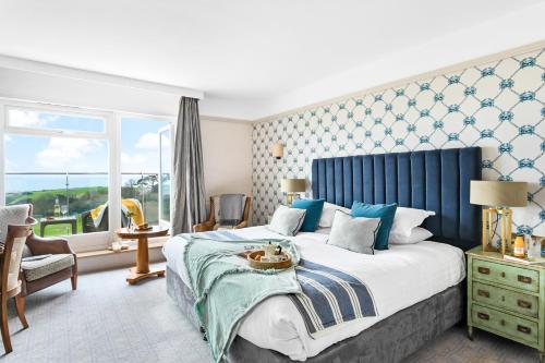 a bedroom with a large bed with a blue headboard at Thurlestone Hotel in Thurlestone