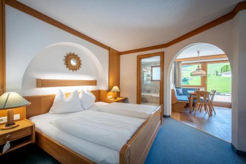 a bedroom with a large bed and a dining room at Eden Appartements in Going am Wilden Kaiser