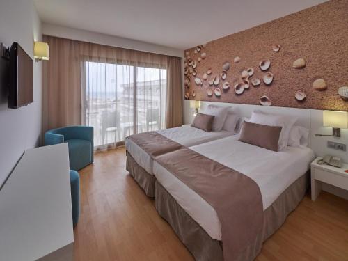 - une chambre avec un grand lit et une grande fenêtre dans l'établissement BQ Can Picafort Hotel, à Can Picafort