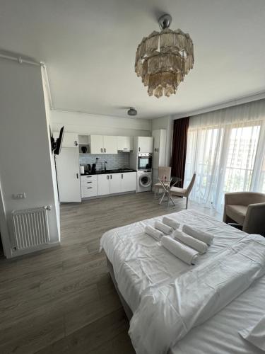 a white bedroom with a large bed and a chandelier at The Chalet in Mamaia Nord