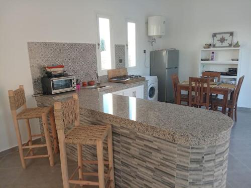 eine Küche mit einer Theke und einigen Stühlen und einer Arbeitsplatte in der Unterkunft Oasis Villa Essaouira in Essaouira