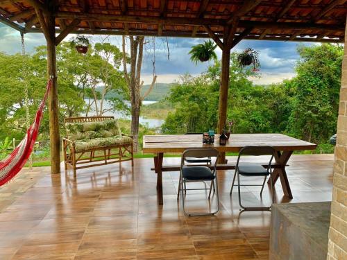 a patio with a wooden table and chairs and a hammock at Suíte Vista do Lago - Casa de Temporada em Corumbá in Alexânia