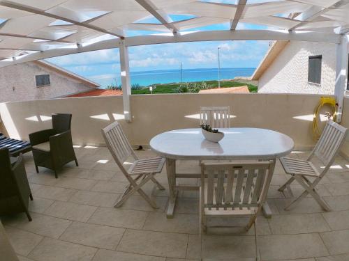 - une table et des chaises sur une terrasse avec vue sur l'océan dans l'établissement Fronte Mare S'Arena Scoada, à Putzu Idu