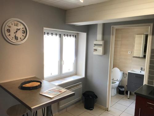 une cuisine avec une horloge sur le mur et des toilettes dans l'établissement Appartement atypique proche theatre place ducale, à Charleville-Mézières