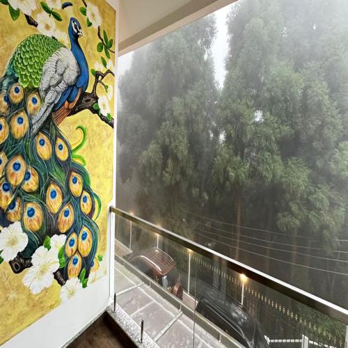 a window with a peacock mural on the wall at Amaira Resort & Farms - Mirik, West Bengal in Mirik