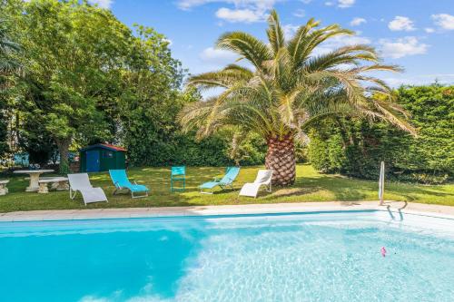 una piscina con sillas y una palmera en Villa Saint-Georges - Welkeys, en Saint-Georges-dʼOléron