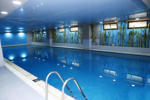 a large swimming pool in a building with blue ceilings at Deluxe Hotel Ganja in Ganja