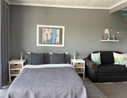 una camera da letto con un letto e un divano di Casual, beachy and 100m to Seals Surf Spot a Cape St Francis
