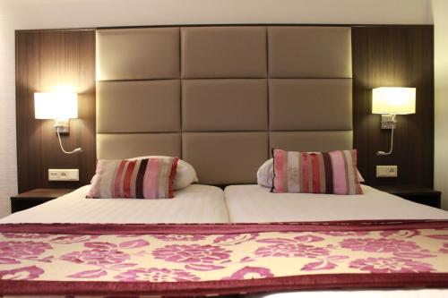 a bedroom with a large bed with two pillows at Hotel Middelburg in Middelburg