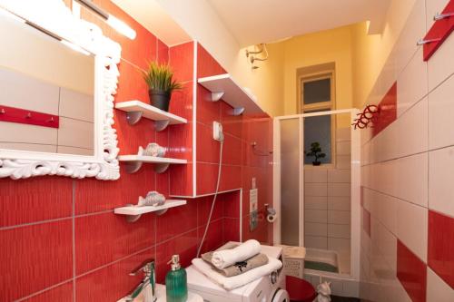 uma casa de banho com paredes vermelhas, um WC e um espelho. em Apartman Zobec Jambrusic em Opatija